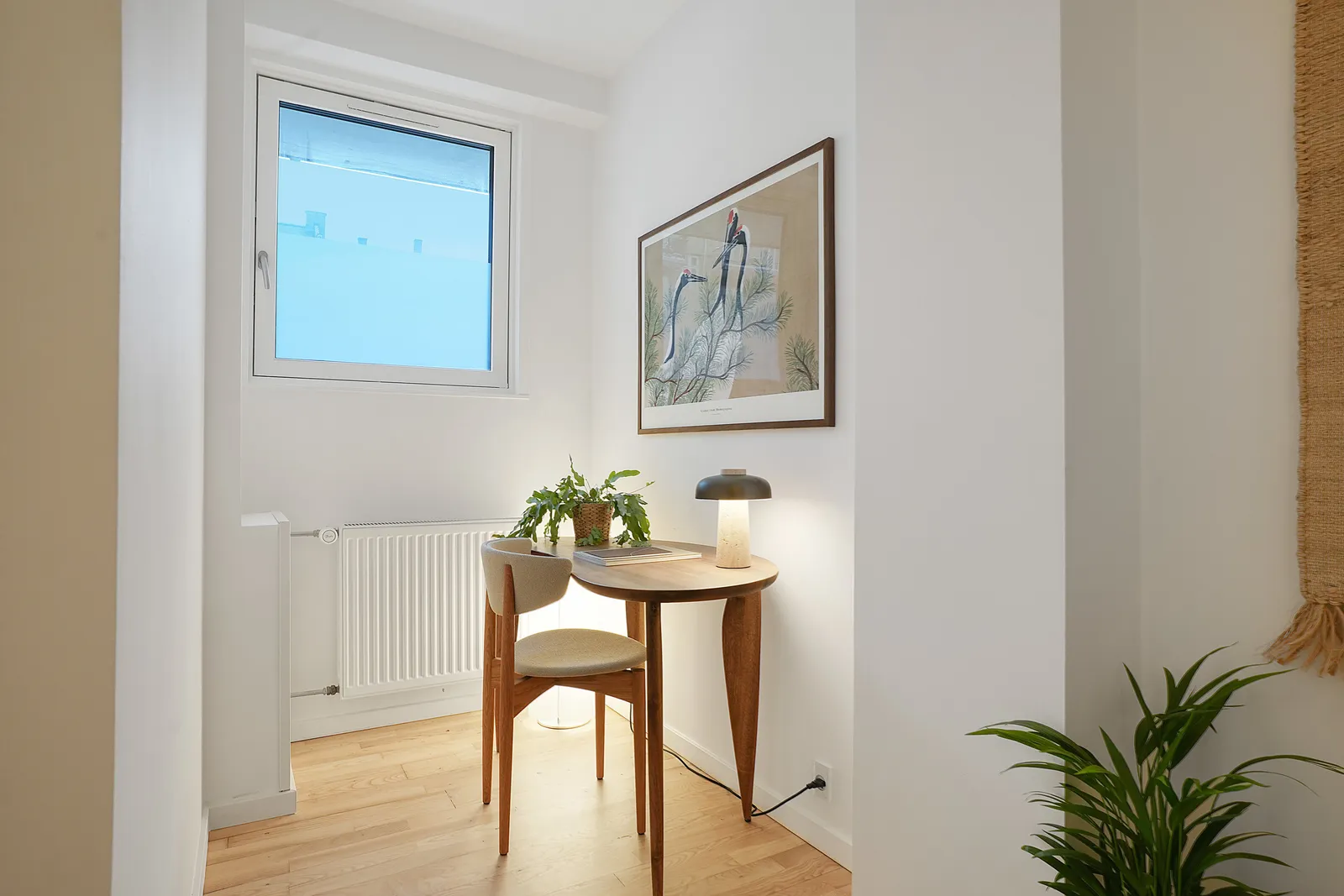 Lys vinduesniche med bord og kunst efter renovering